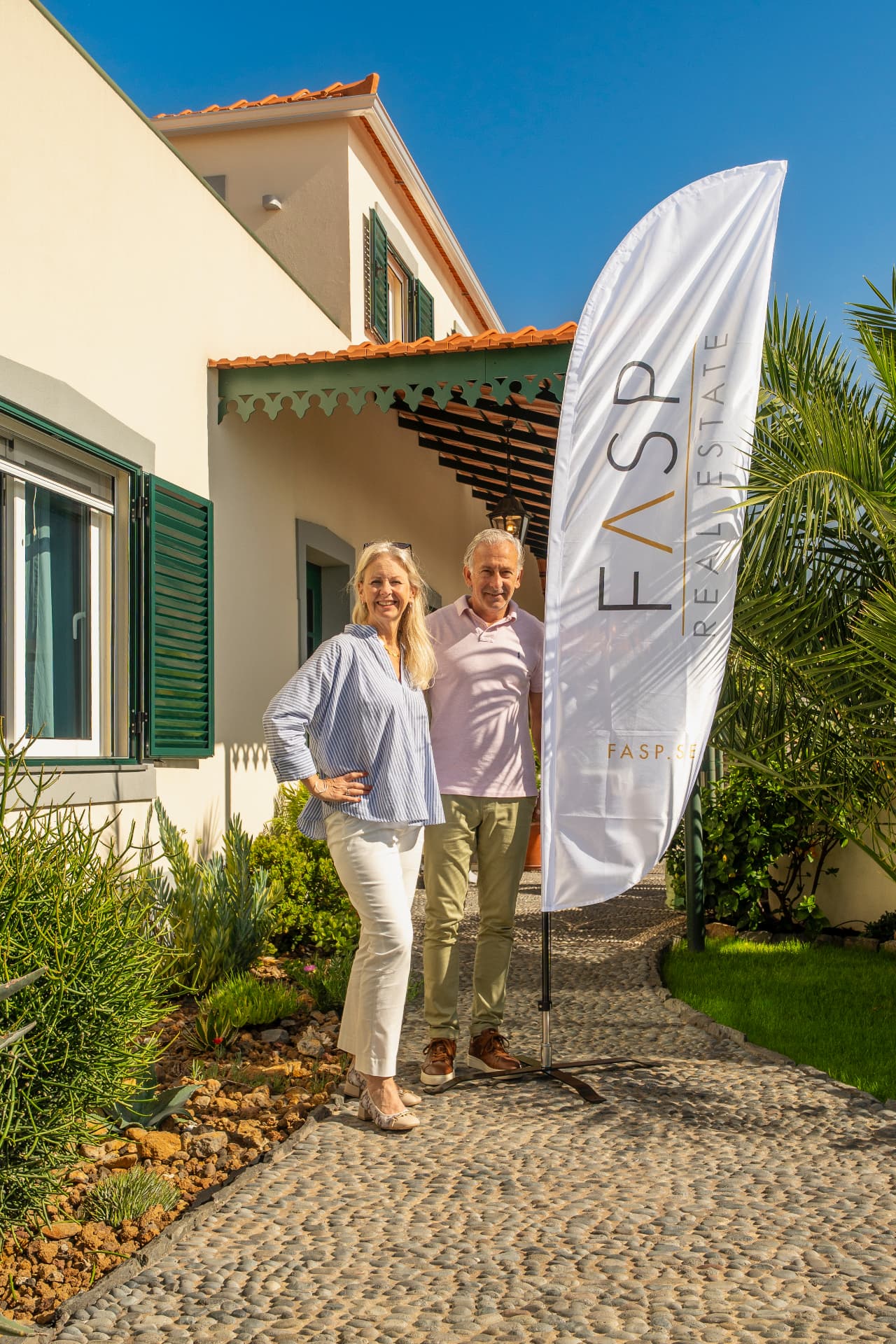 The founders of FASP standing on a cobblestone path in front of their villa in Portugal